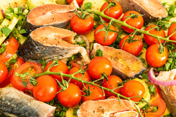 Chopped raw vegetables and pieces of fish in a baking sheet for cooking vegetable roast with trout