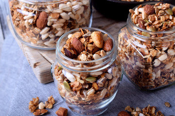 Homemade granola with different nuts and seeds in glass jars 