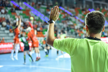 Handball referee gives signal playing for time during handball match. - obrazy, fototapety, plakaty