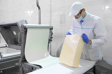 man in a white robe and a cap make an inspection of dairy products
