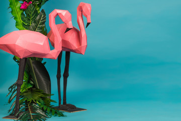Pink flamingo tropical leaves decor in the studio on a blue background. Summer abstract art