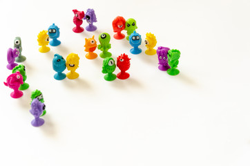 Small colored rubber monsters toys on a white background. Cute monster figures stand in pairs. Children's background