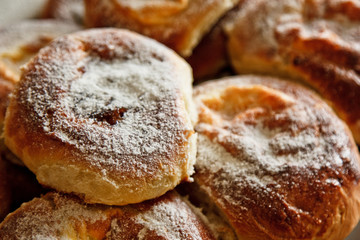 buns in plates full of freshly baked cheesecakes sprinkled with powdered sugar on the kitchen table. cooking baking. baking preparation stage. breakfast close up top view