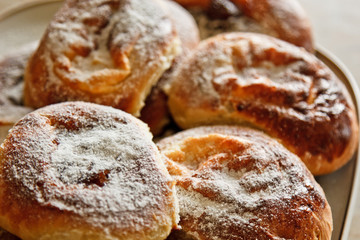 buns in plates full of freshly baked cheesecakes sprinkled with powdered sugar on the kitchen table. cooking baking. baking preparation stage. breakfast close up top view