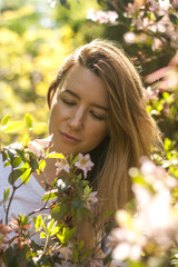 Naklejka premium Young woman in blossoming bush in the sunny summer day