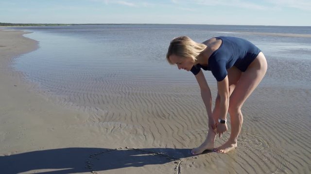 Woman doing heart on the sand, steadycam shot,