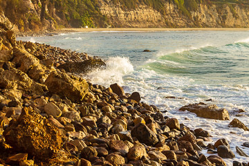 wave breaking on rocky shore towards sandy beack