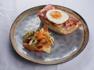 Sandwich with a fried egg, bacon, cheese and vegetables.