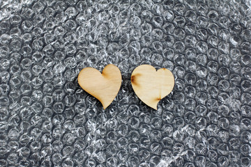 Two wooden hearts lie on a bubble wrap film top view. wooden wedding