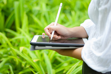 Women read or analyze reports on tablet computers. In the midst of nature