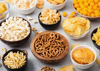 All classic potato snacks with peanuts, popcorn and onion rings and salted pretzels in bowl plates...