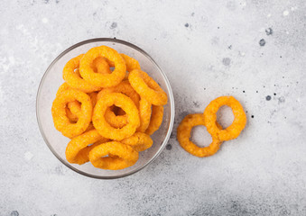 Classic crispy onion rings fast food snack in glass bowl on light kitchen table background.