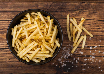 Salt and vinegar potato sticks in white bowl, classic snack on wooden background.