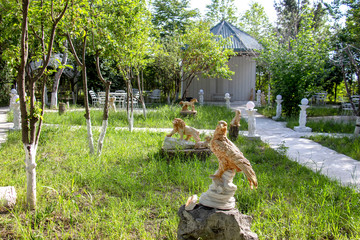 White alley in the park, ceramic species of animals on the green lawn