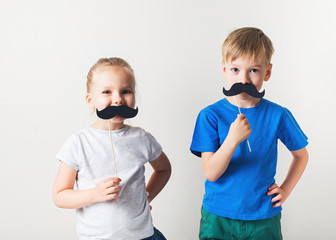 Fathers day concept, two little caucasian kids with moustache on white background