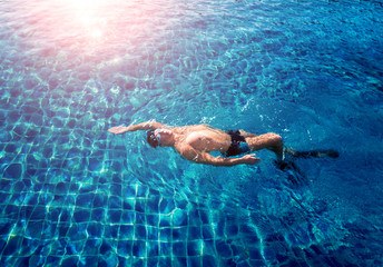 Young athletic man swimming in the swimming pool