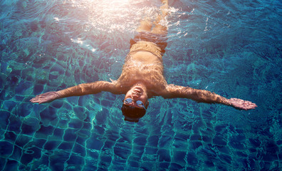 Young athletic man swimming in the swimming pool