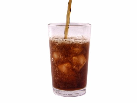 Pouring cola drink in glass with ice