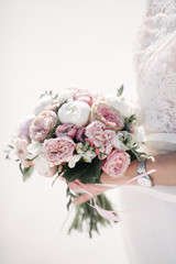 Bride in a wedding dress holding a wedding bouquet in her hands close-up