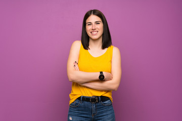 Young woman over isolated purple wall keeping the arms crossed in frontal position