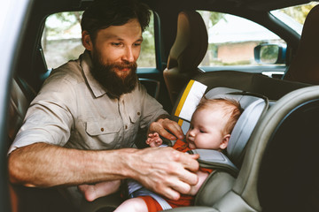 Father putting baby in safety car seat happy family vacation road trip lifestyle child care...