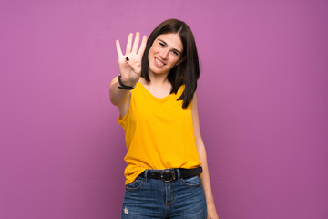 Young woman over isolated purple wall happy and counting four with fingers