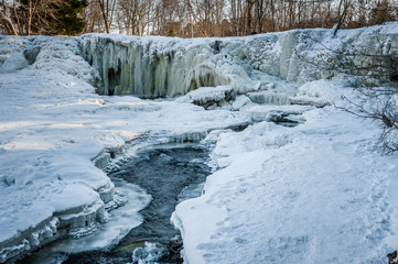 Famous waterfall in Estonia. Keila-Joa Schloss Fall. Partly frozen waterfall by winter. Estonia. Winter landscape.