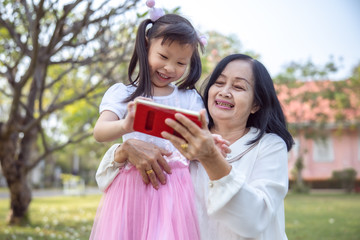 asian two grandmother and grandchildren relaxing in the garden with smartphone on holding hand