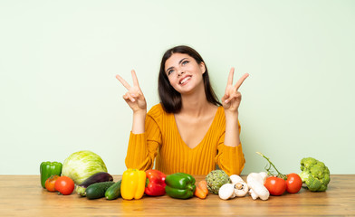 Fototapeta premium Teenager girl with many vegetables showing victory sign with both hands