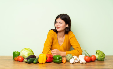 Fototapeta premium Teenager girl with many vegetables making doubts gesture looking side