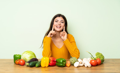 Teenager girl with many vegetables smiling with a happy and pleasant expression