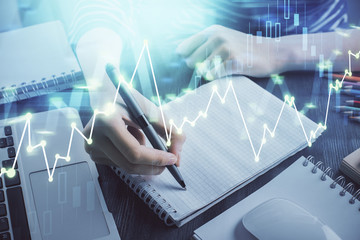 Financial chart drawn over hands taking notes background. Concept of research. Double exposure