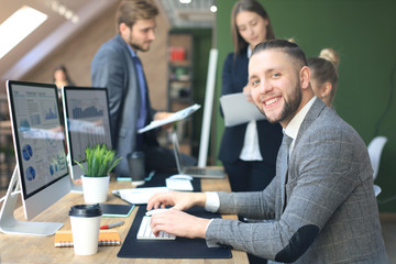 Businessman with colleagues in the background in office.