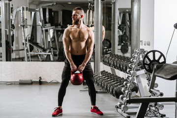 Muscular man doing exercises with a big dumbbell in the gym