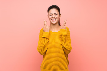 Teenager girl  over isolated pink wall with fingers crossing
