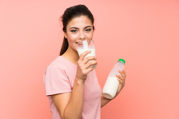 Teenager girl  over isolated pink wall having breakfast milk