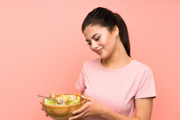 Teenager girl  over isolated pink wall with salad