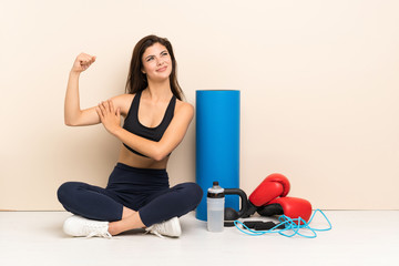 Teenager sport girl sitting on the floor doing strong gesture