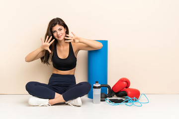 Teenager sport girl sitting on the floor counting nine with fingers