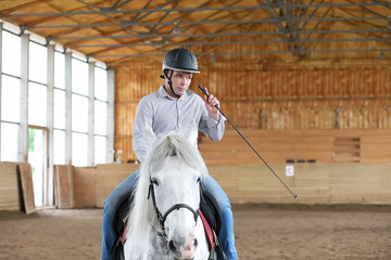 People on a horse training in a wooden arena