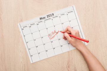 cropped view of recruiter writing with red marker on print calendar with job interview lettering