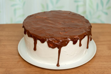 Birthday cake with chocolate syrup. Background with leaf design on white curtain.