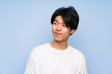 Asian man on isolated blue background standing and looking to the side