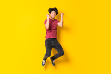Fototapeta na wymiar Asian man jumping over isolated yellow wall