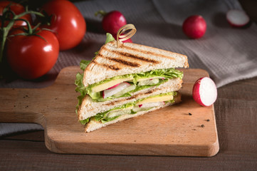 Club sandwich with vegetables on rustic background