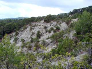 Panorama of the sand slope of a low mountain ridge covered with poor vegetation on the background of cloudy autumn sky.