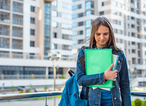 Back to school student teenager girl holding books and note books wearing backpack. Outdoor portrait of young teenager brunette girl with long hair. girl on city