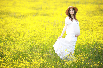 Pregnant woman in a dress in a field of flowers