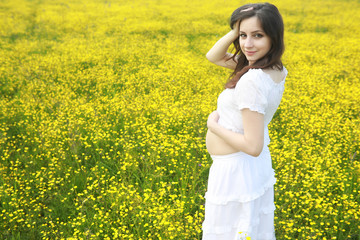 Fototapeta premium Pregnant woman in a dress in a field of flowers