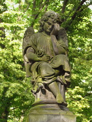 Fototapeta na wymiar Statue of small angel on a desert grave, Olsany cemetary, Prague, Czech republic